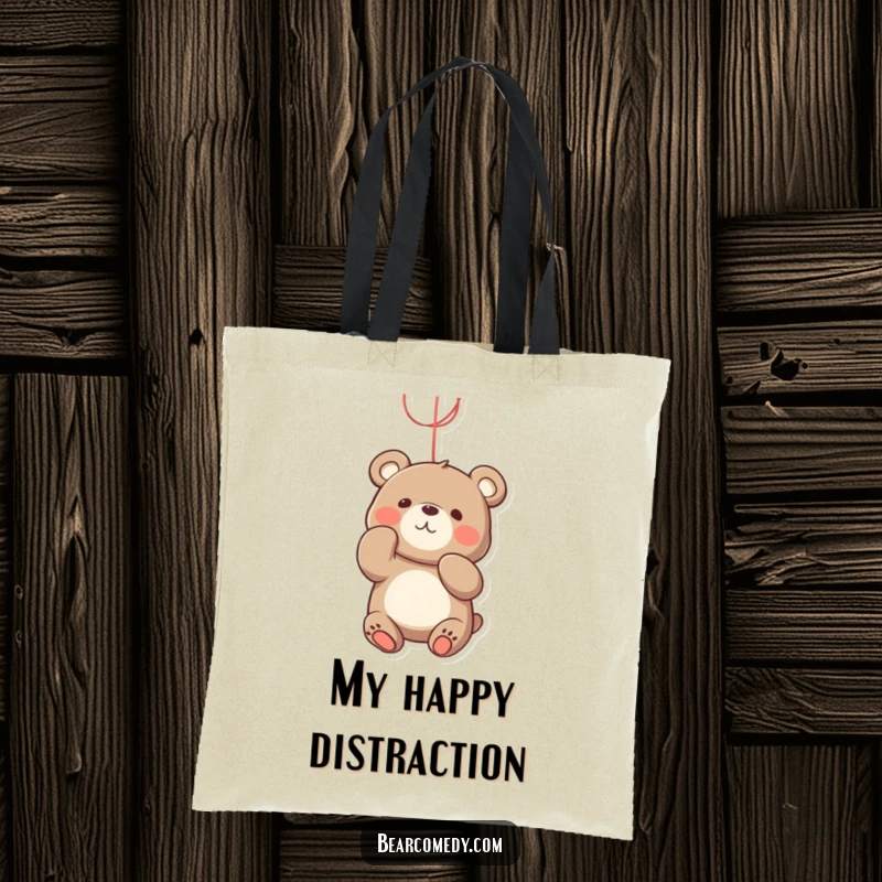 Funny bear tote bag featuring a playful bear character batting at a bright, dangling string with an engaged expression.