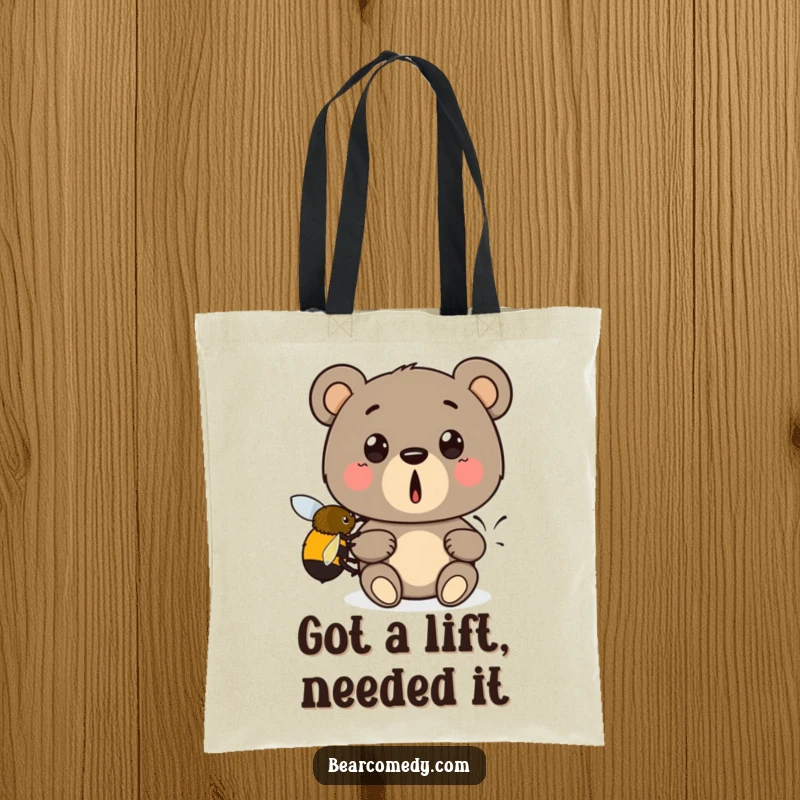 Funny tote bag design: A surprised bear is gently boosted by a tiny bumblebee, a comical and delightful visual.